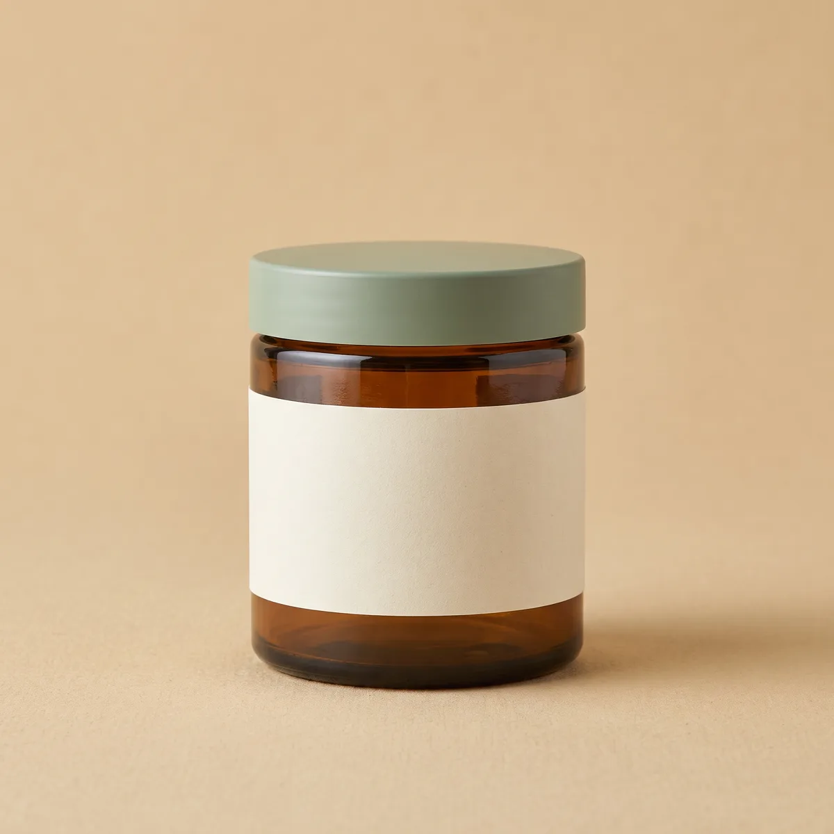 An amber Tidefall jar with a sage lid, alone on a plain oat backdrop